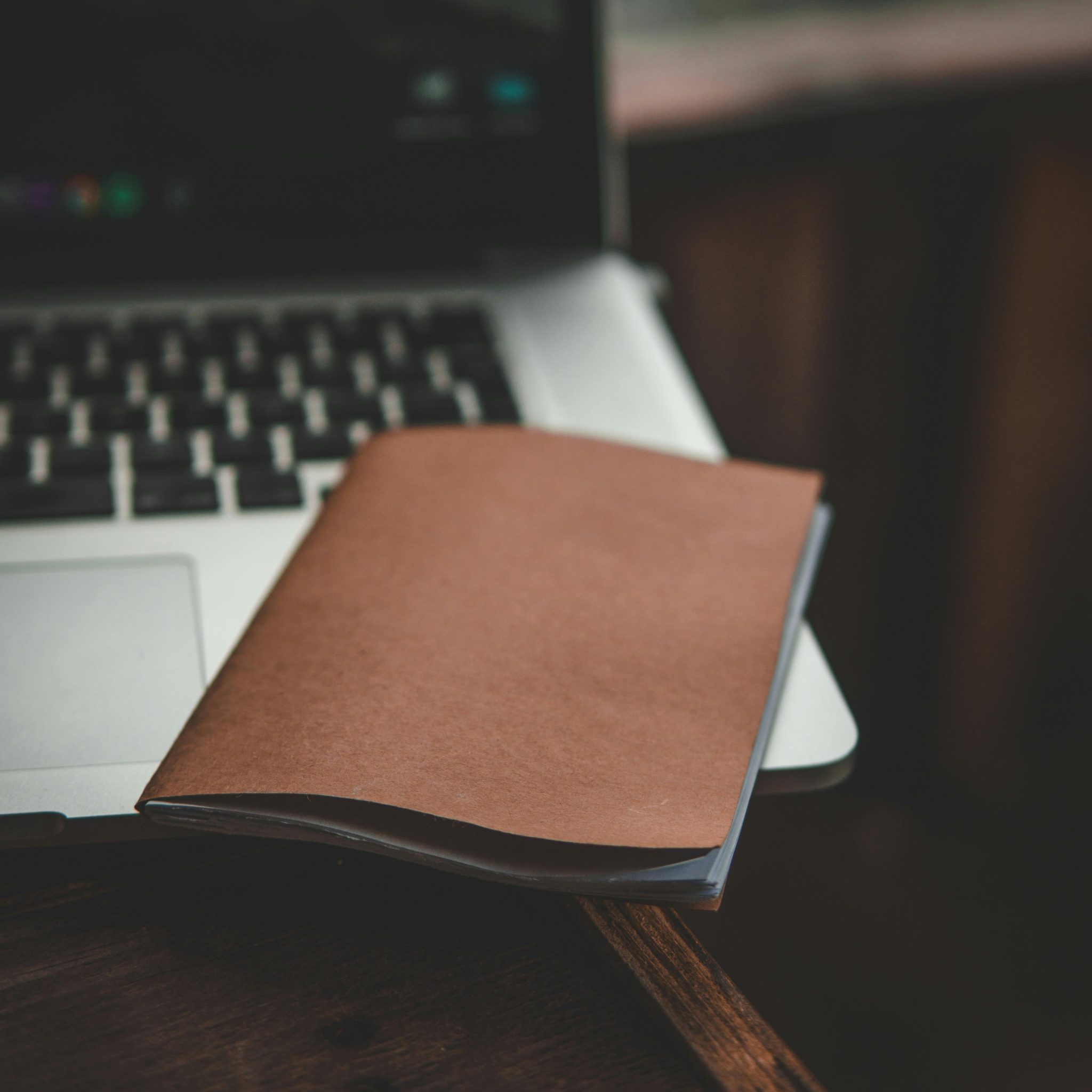 A brown notebook placed on a laptop in a cozy indoor setting, perfect for productivity.